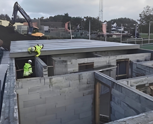 Arbeidere på et klubbhus under bygging med vegger av isolasjonsstein
